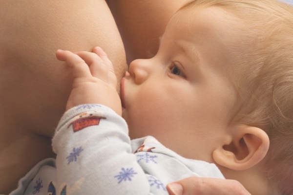 A caucasian newborn baby boy breastfeeding .
