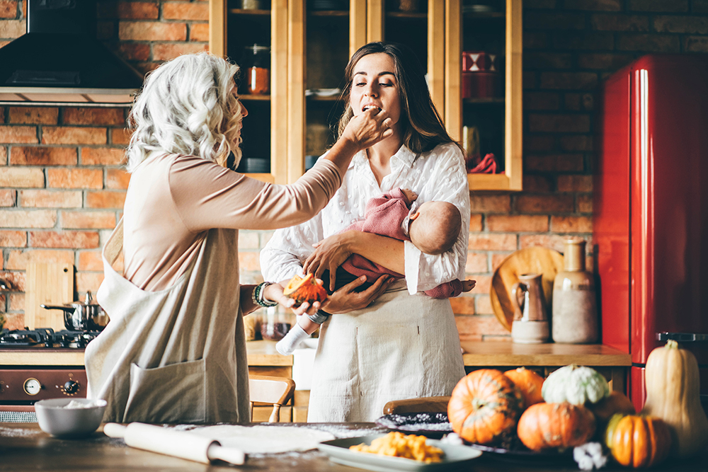 Brunette with long loose flowing hair holds baby and senior gran