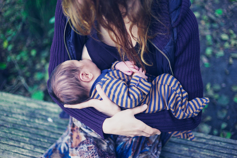 Mother breastfeeding baby in forest