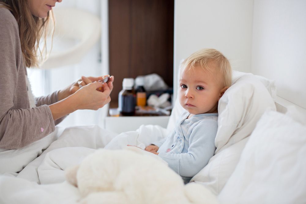 Mother and baby in pajamas, early in the morning, mom taking care of her sick toddler boy